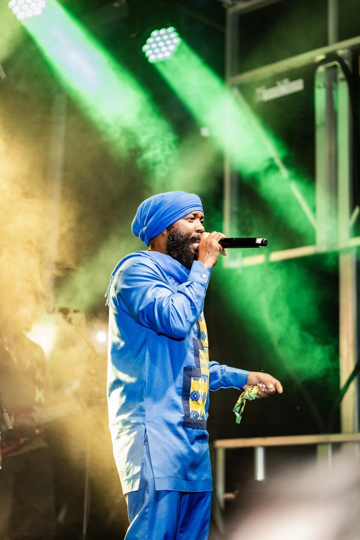 Warrior King in blue performing under green stage lights, 2024