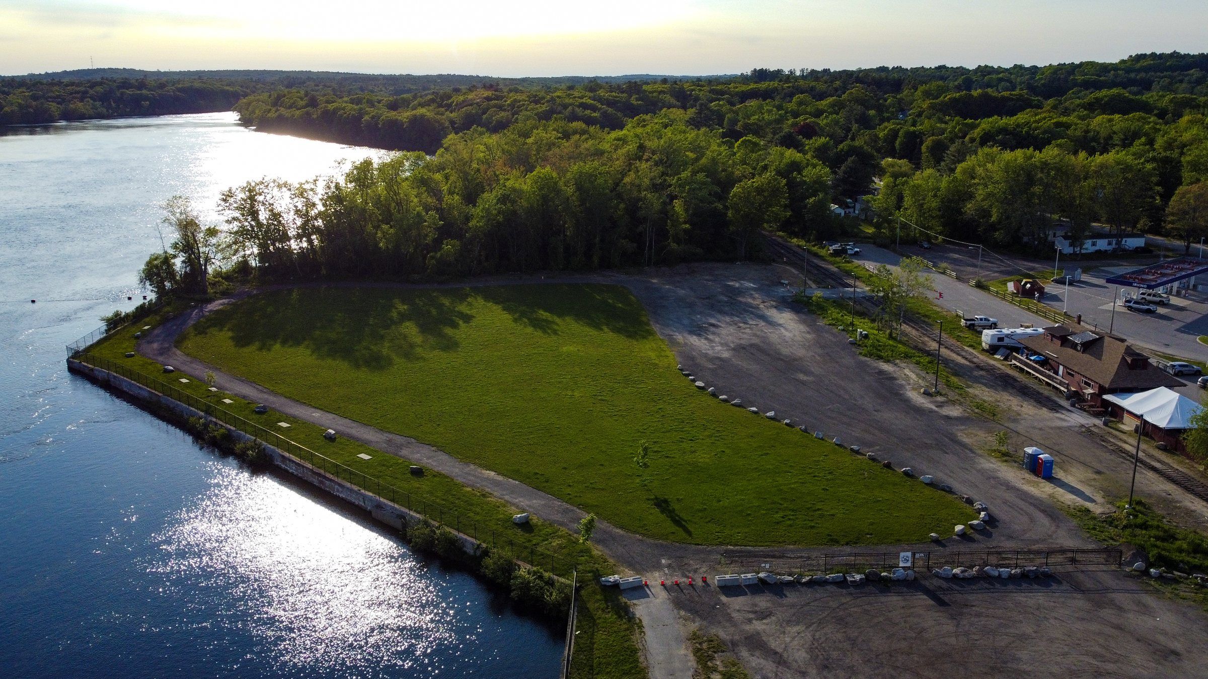 The riverfront lawn in low evening light, with the river curving away into the trees
