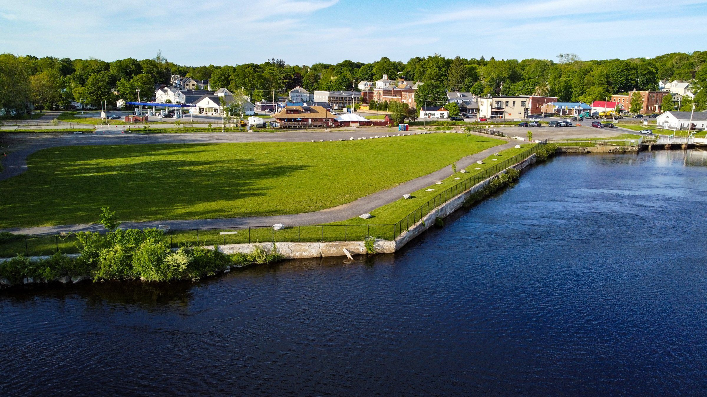 The festival lawn from the river, with the shops of Main Street, Lisbon Falls along the far edge