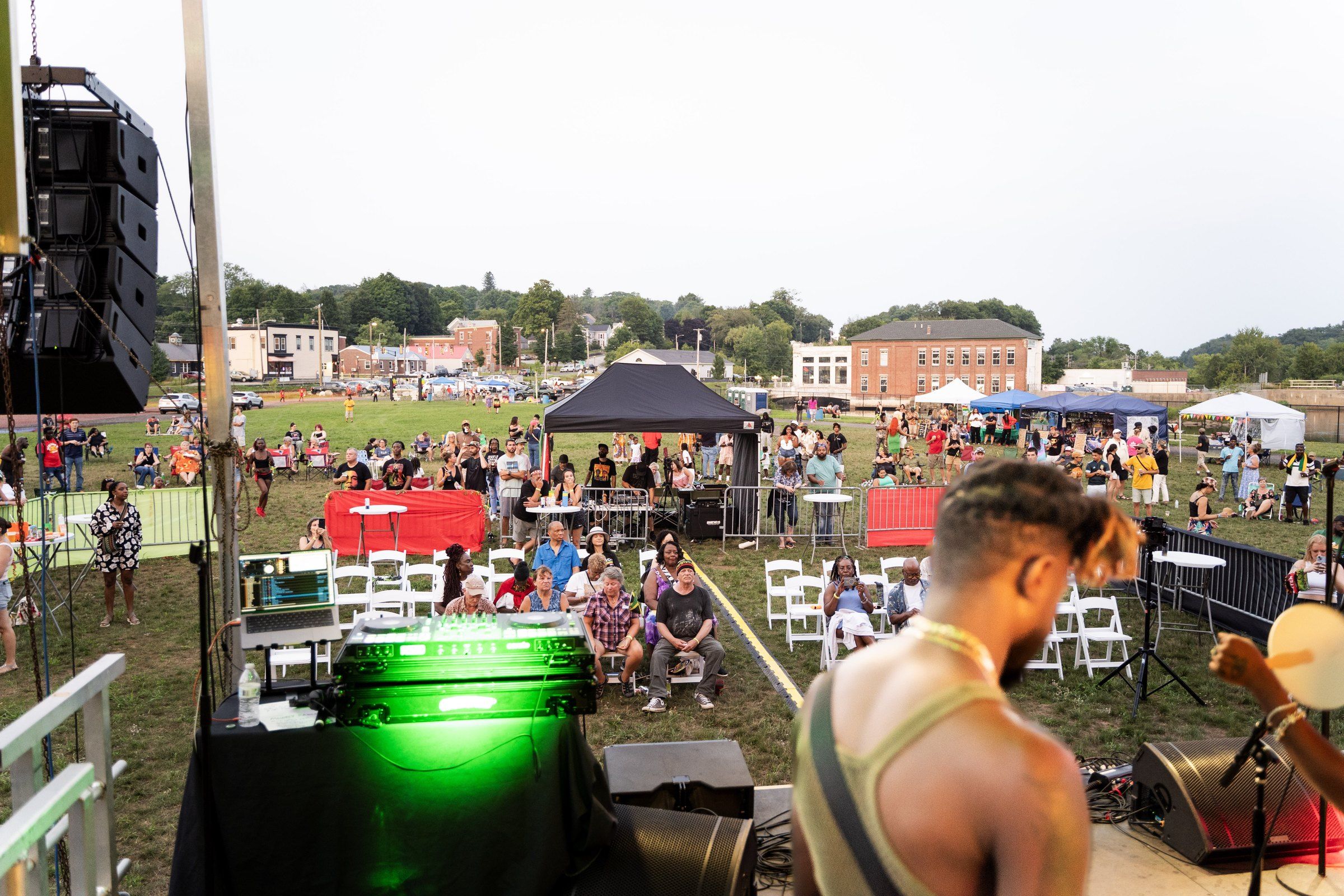 The view from the stage: the crowd on the Worumbo lawn with Lisbon Falls brick buildings behind, 2024